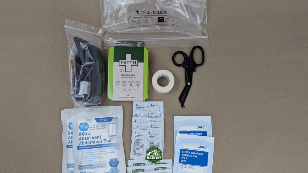 First aid kit items spread out with EcoEnclose poly bag on kraft paper background
