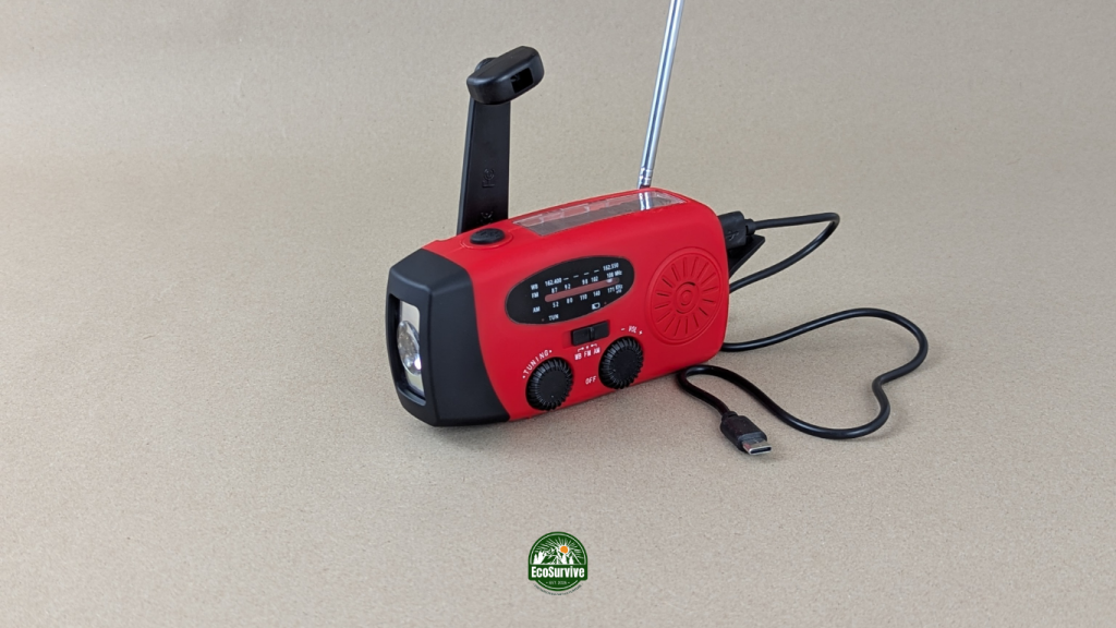 Close-up of hand-crank emergency radio with flashlight, solar panel, and phone charger cable